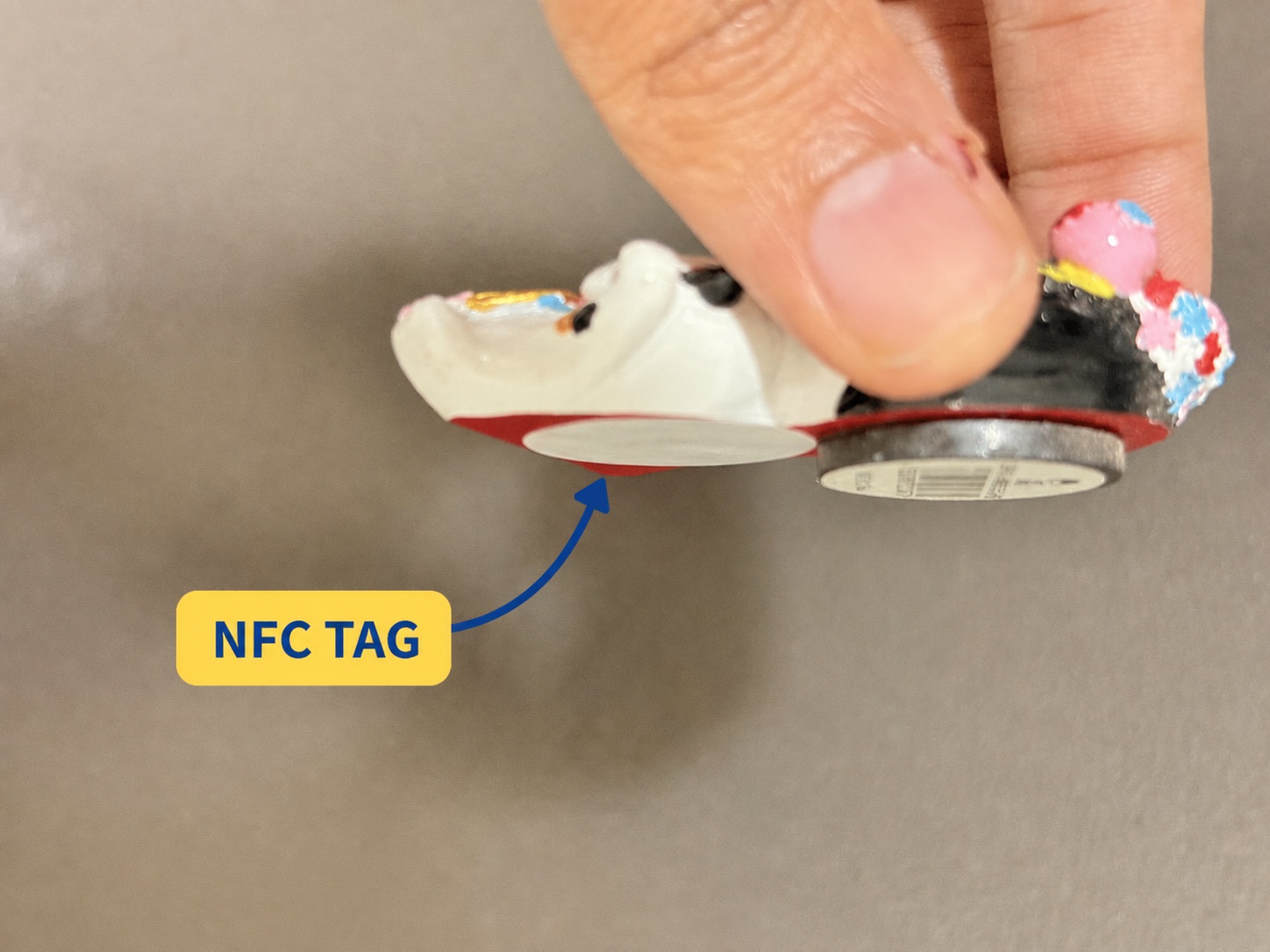 Arrow identifying the NFC sticker beside the raised magnetic puck on the back of a souvenir fridge magnet